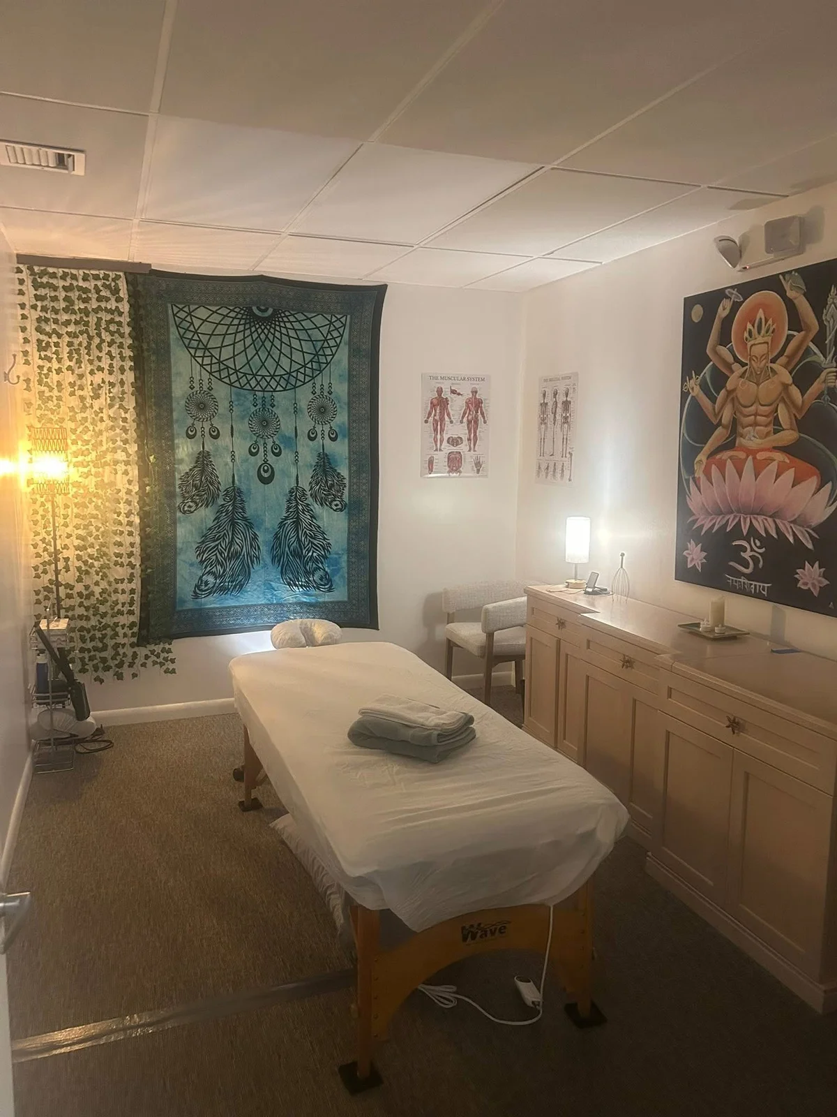 Van’s massage studio with a cream-covered massage table, warm lamps, and wall tapestries